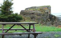 brown wooden bench on green grass field near brown rock formation during daytime